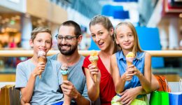 Family eating ice cream in shopping mall with bags